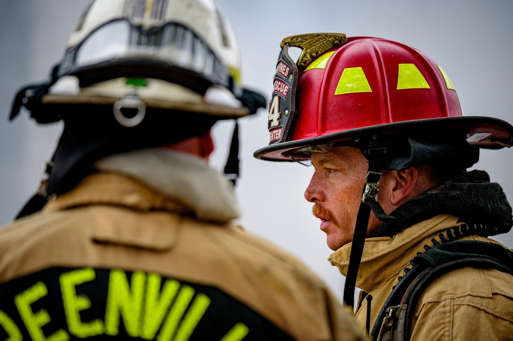 Dos bomberos con casco hablando durante una intervención