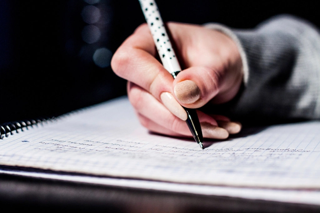 Mano tomando apuntes a bolígrafo en un cuaderno de anillas